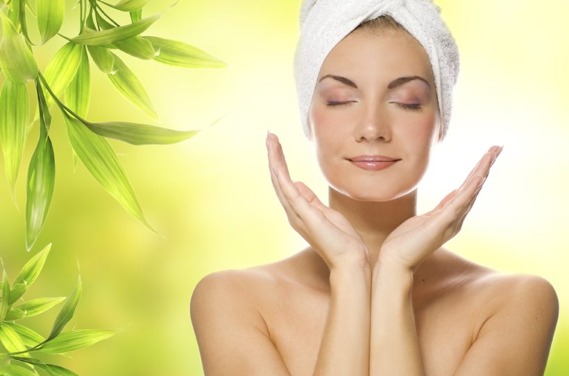 Beautiful young woman applying organic cosmetics to her skin